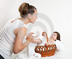 Mother talk with baby in basket on white towel, family concept