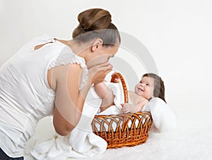 Mother talk with baby in basket on white towel, family concept