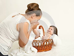 Mother talk with baby in basket on white towel, family concept, yellow toned