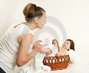 Mother talk with baby in basket on white towel, family concept, yellow toned