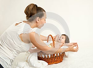 Mother talk with baby in basket on white towel, family concept, yellow toned