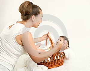 Mother talk with baby in basket on white towel, family concept, yellow toned