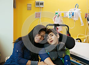 Mother talking with disabled son in wheelchair at hopsital room