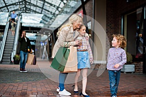 Mother talking with her little kids during shopping at shopping centre