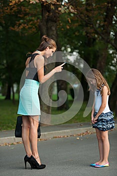 Mother talking to naughty girl on a street in park