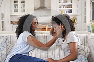Mother Talking With Unhappy Teenage Daughter On Sofa photo