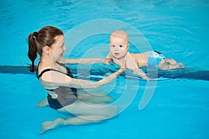 Mother teach baby to swim in water pool. Swimming lessons for children