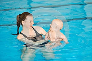 Mother teach baby to swim in water pool. Swimming lessons for children