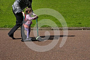 Mother teach her child to ride a scooter