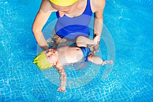 Mother teach small baby infant to float on back