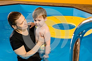 Mother teaches Child To Swim In indoor Pool