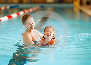 Mother teaches child to swim in pool