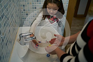 Mother teaches daughter to wash her hands with virus models in water