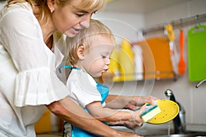 Mother teaches her little child son to wash-up