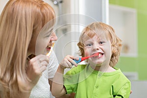Mother teaches her little son how to brush teeth