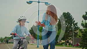 Mother teaches ride bike little daughter child. daughter kid with mom operate two-wheeled children.Mom is happy when her