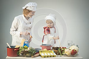 Mother teaches son to cook on light background.