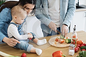 Mother teaching baby rules of using knives in kitchen