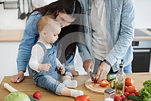 Mother teaching baby rules of using knives in kitchen