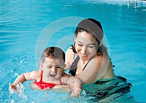 Mother teaching baby swimming photo