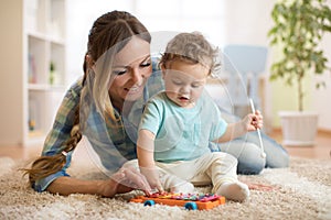 Mother is teaching child how to play xylophone toy