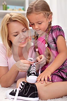 Mother teaching child how to tie shoes