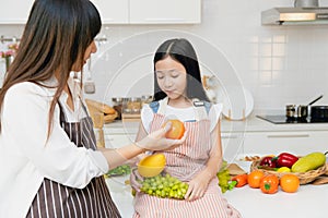 Mother teaching child to eating fruit and advise to eat orange for vitamin C and healthy food