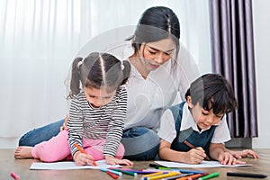 Mother teaching children in drawing class. Daughter and son painting with colorful crayon color in home. Teacher training students