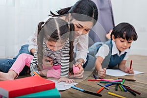 Mother teaching children in drawing class. Daughter and son painting with colorful crayon color in home. Teacher training students