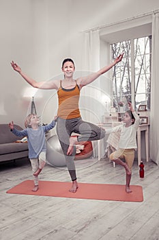 Mother teaching children keeping the balance in a yoga position
