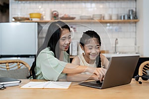 Mother teaching children to do their homework at home. Happy asian family using the laptop together at home. Young asian