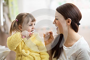 Mother teaching daughter child teeth brushing in bathroom