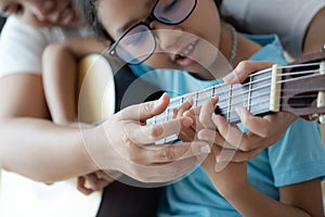 Mother teaching the daughter learning how to play acoustic classic guitar for jazz and easy listening song select focus shallow