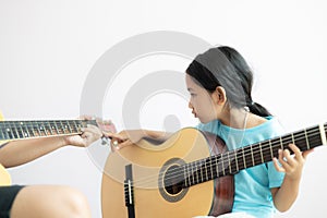 Mother teaching the daughter learning how to play acoustic classic guitar for jazz and easy listening song select focus shallow