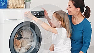 Mother teaching daughter operate washing machine