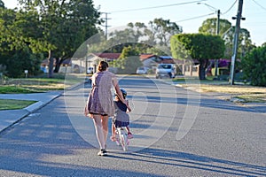 Mother teaching daughter to ride bike in city street