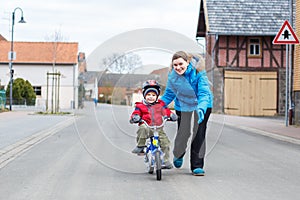 Mother teaching her 3 years old son to ride a bike