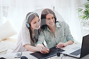 Mother teaching her daugher to draw by stylus photo