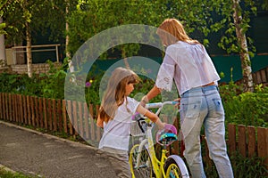 Mother teaching her daughter how to ride a bicycle in the park.