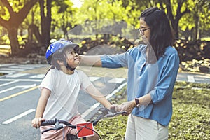 Mother teaching her daughter to ride bicycle in park. Family outdoor on bike ride