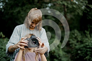 Mother is teaching her young daughter to use a camera outside in spring nature