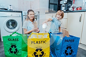 Mother is teaching kid how to recycle help the boy aware environmental importance - mom educates son sort garbage into