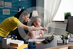 Mother teaching little pupil about school lesson at home