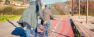 Mother teaching son to ride a bike in cycleway