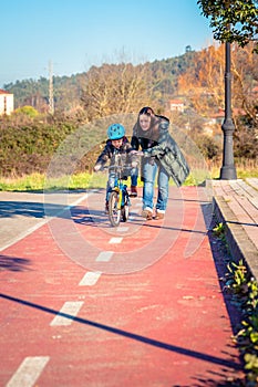 Mother teaching son to ride a bike in cycleway