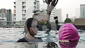 Mother is teaching and trainer her daughter to swim in condominium pool.