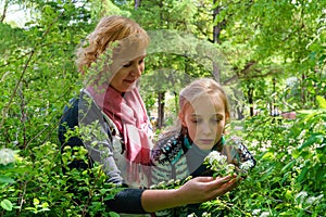 Mother and teen daughter among flowers in the park