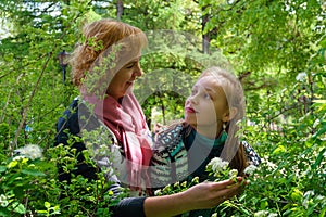 Mother and teen daughter among flowers in the park