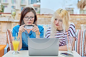 Mother and teenage daughter doing online shopping together using laptop