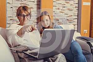 Mother and teenage daughter looking at laptop together